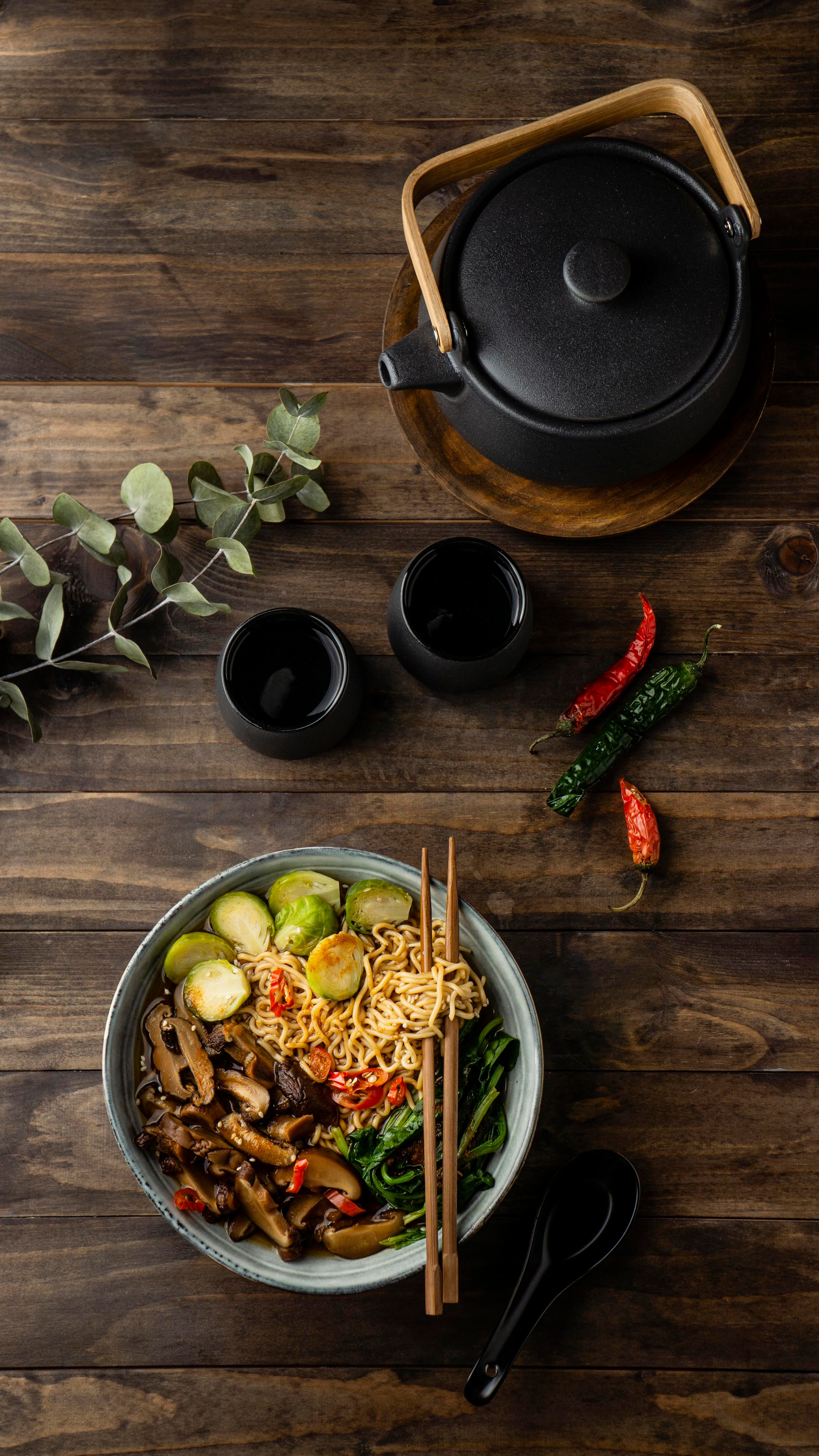 Ramen bowl on wooden table with teapot and decorative elements
